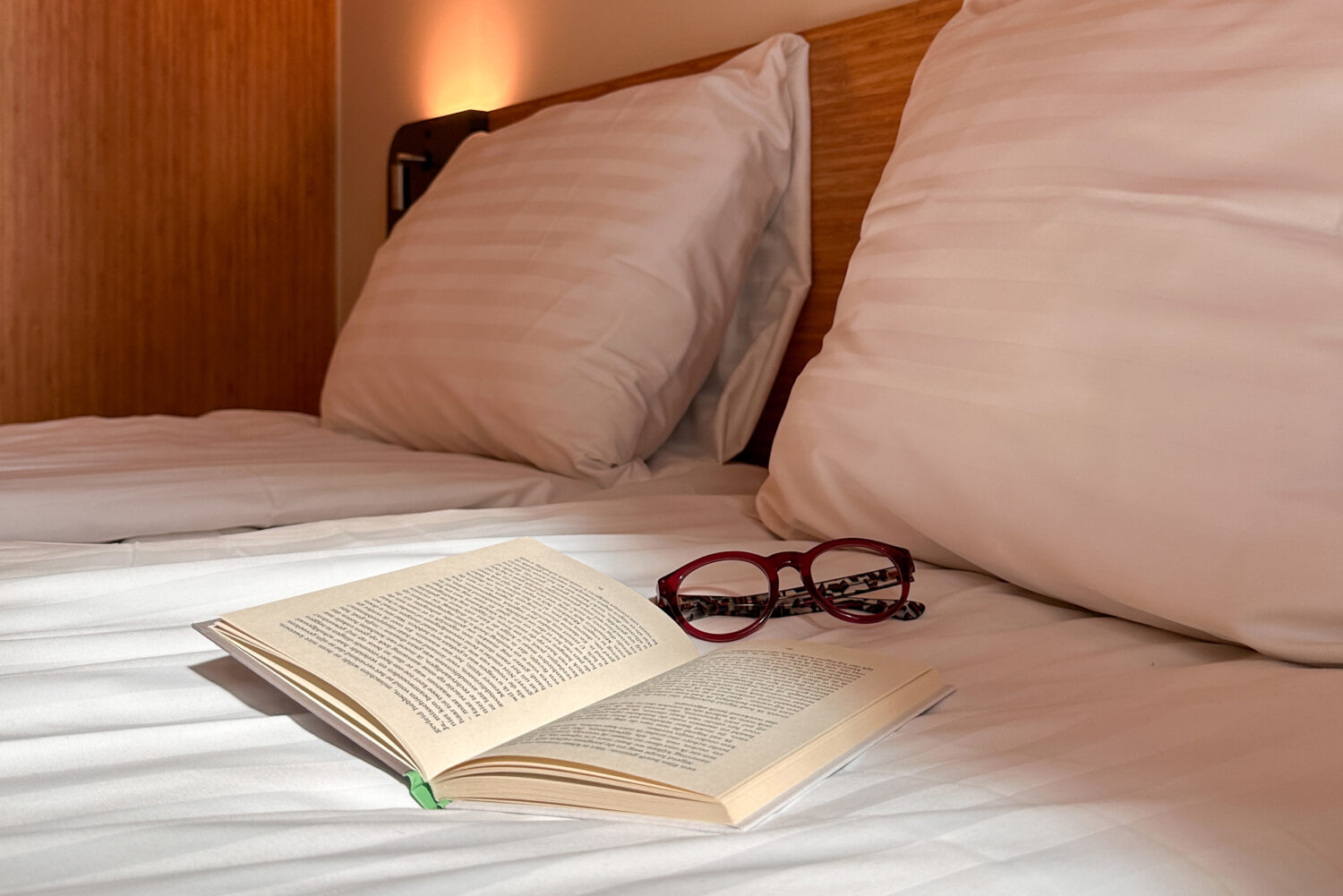 Book and glasses on a bed