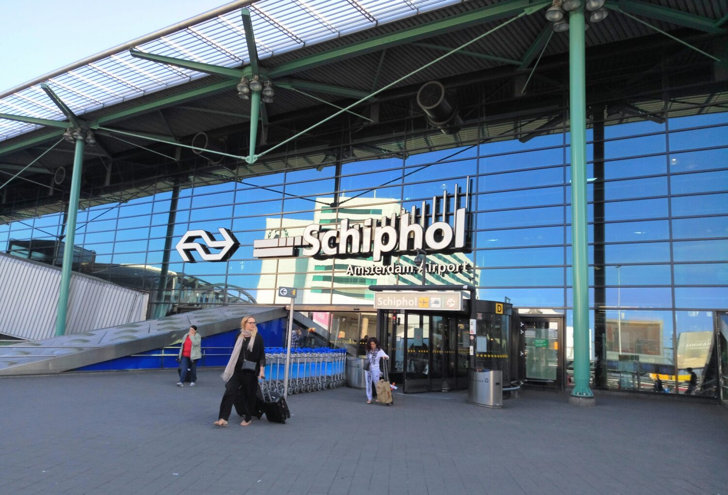 Entrance of the Amsterdam Airport Schiphol with a few passengers 