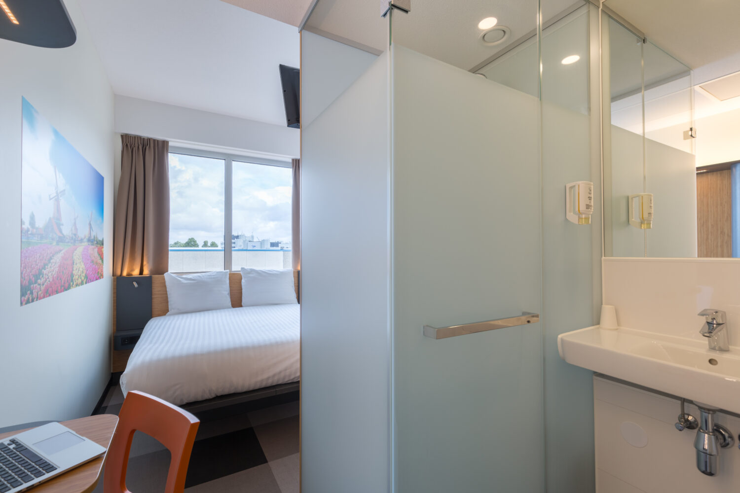 Hotel room with bed, working area, built-in shower and a sink