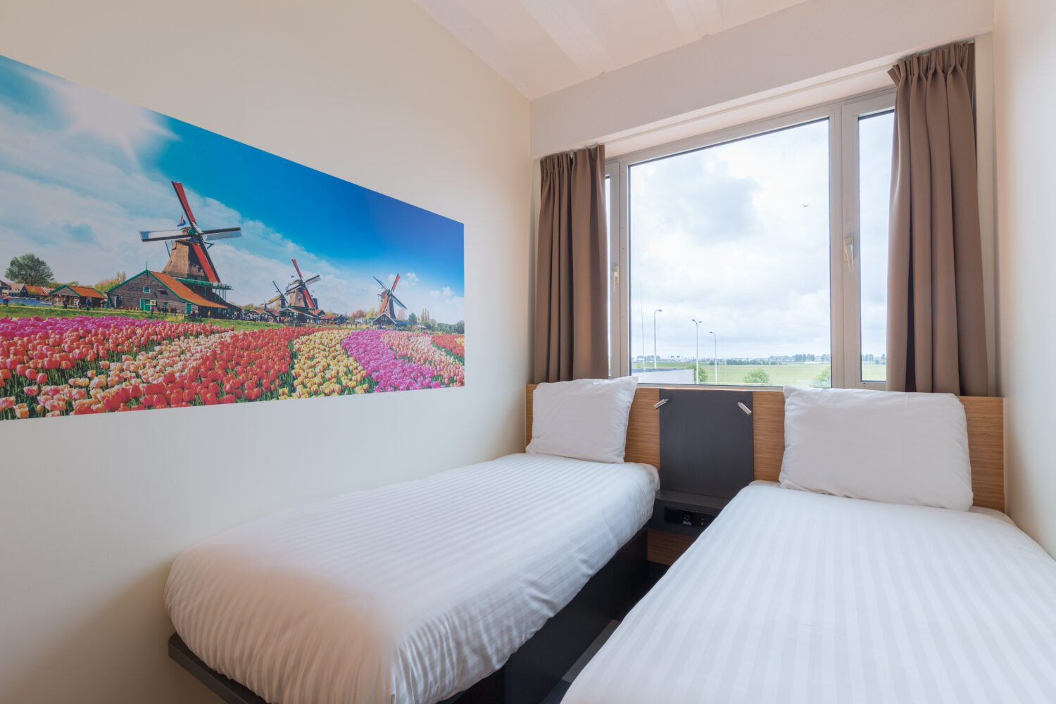 Hotel room with two single beds and a view of a green field