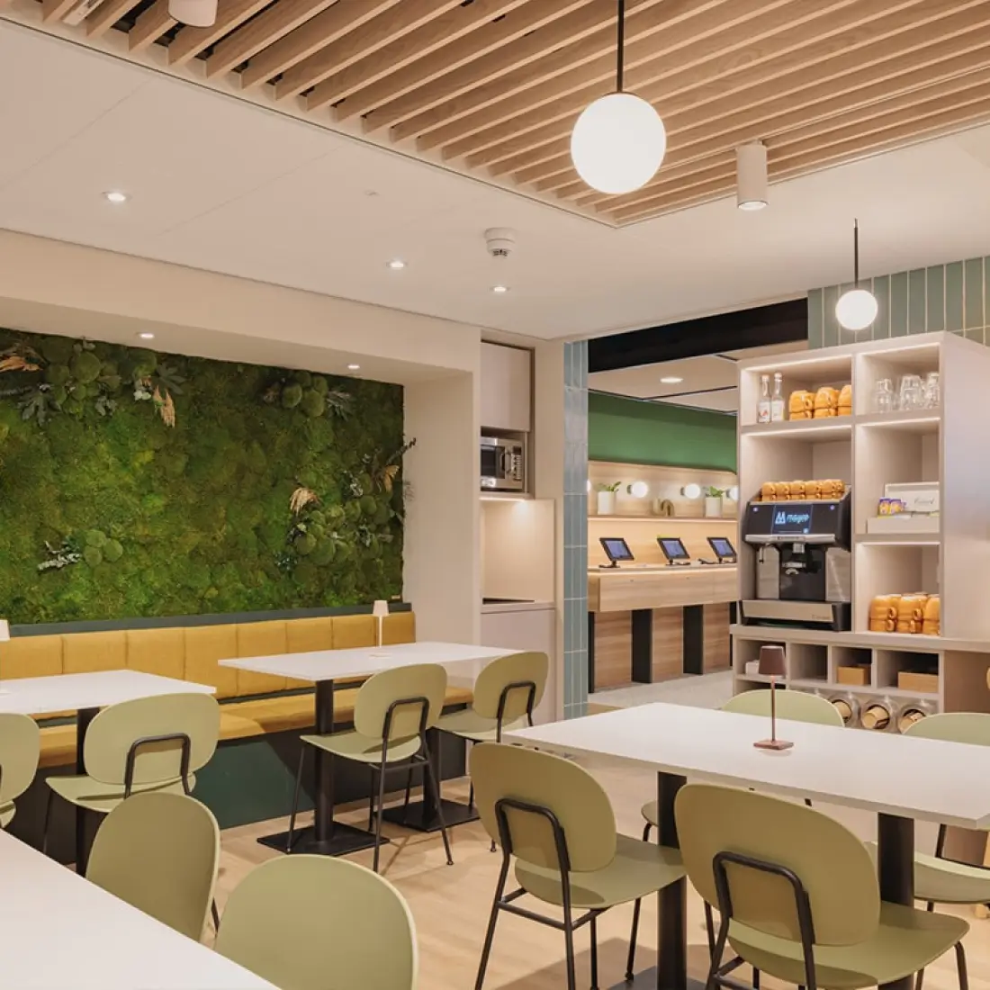 Maxhotel café with green moss wall, self-service station, and grab-and-go options for guests