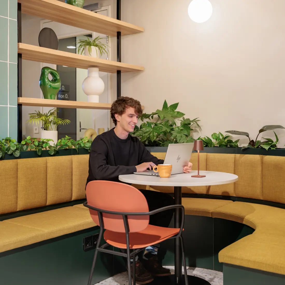 Gasten gebruiken hun laptop met gratis WiFi in de milieuvriendelijke loungeruimte van Maxhotel met planten en modern meubilair