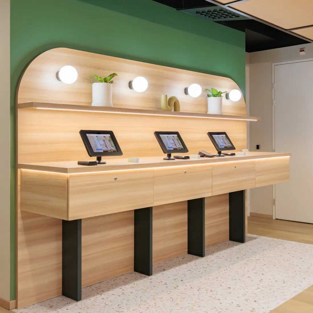 Maxhotel self-service incheckkiosken met digitale schermen en milieuvriendelijke houten designelementen
