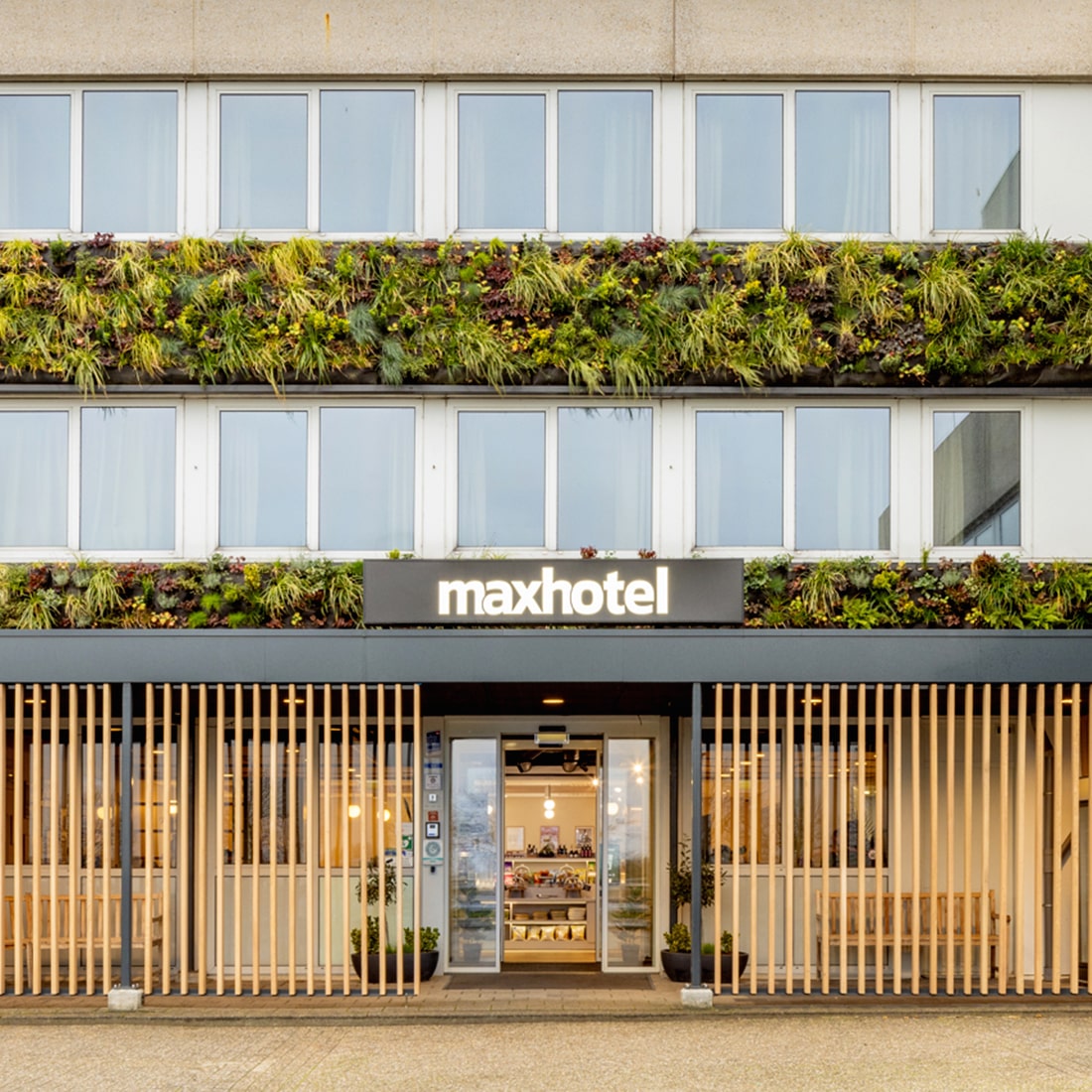 The modern Maxhotel exterior with lush green vertical gardens and a welcoming entrance.